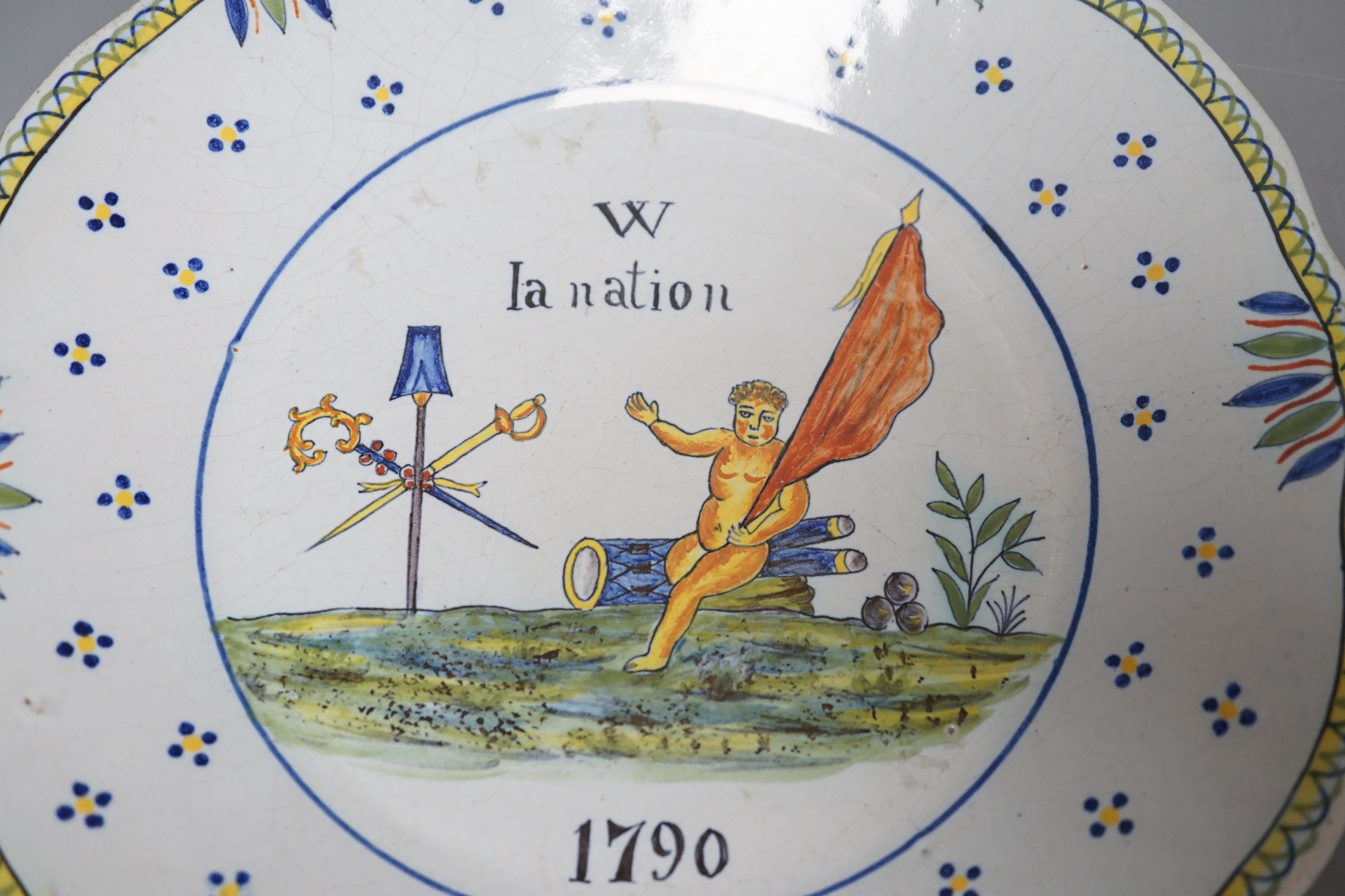 A pair of French faience plates - ‘la nation’, 1790, and ‘je suis las de les Porter’, 1791 - 24cm diameter